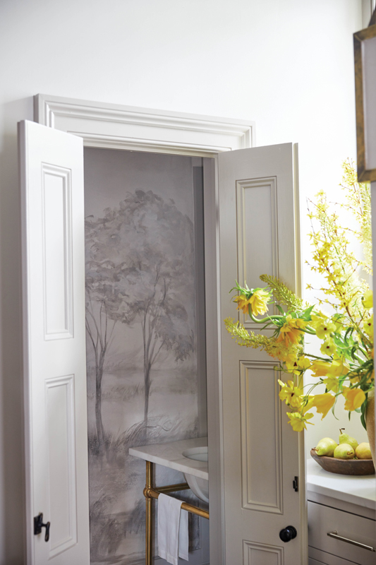 The doorway leads to the kitchen, where this compact half bath was treated to a bucolic mural by Kollar.