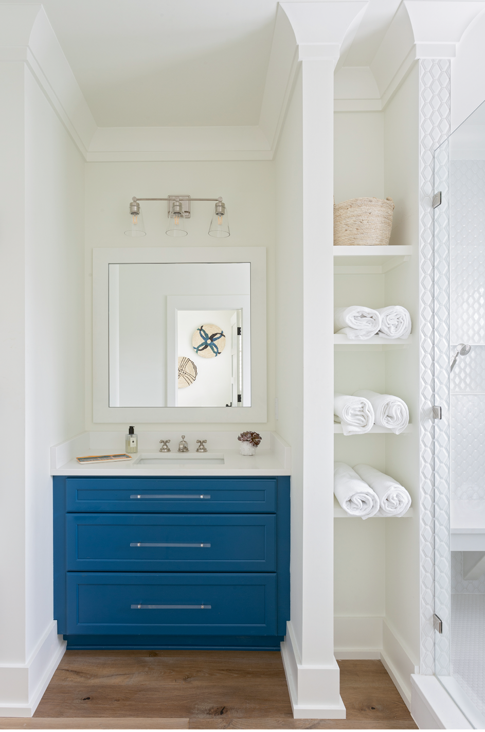 A Pop of Color: The daughters share this remodeled bathroom, which was redesigned to afford a much larger shower space, complete with a bench and finished in subway tile from Melcer Tile. Custom cabinetry from Spartina Cabinets is offset by the Benjamin Moore “Simply White” wall color and illuminated by a vanity light in polished nickel from Carolina Lanterns.