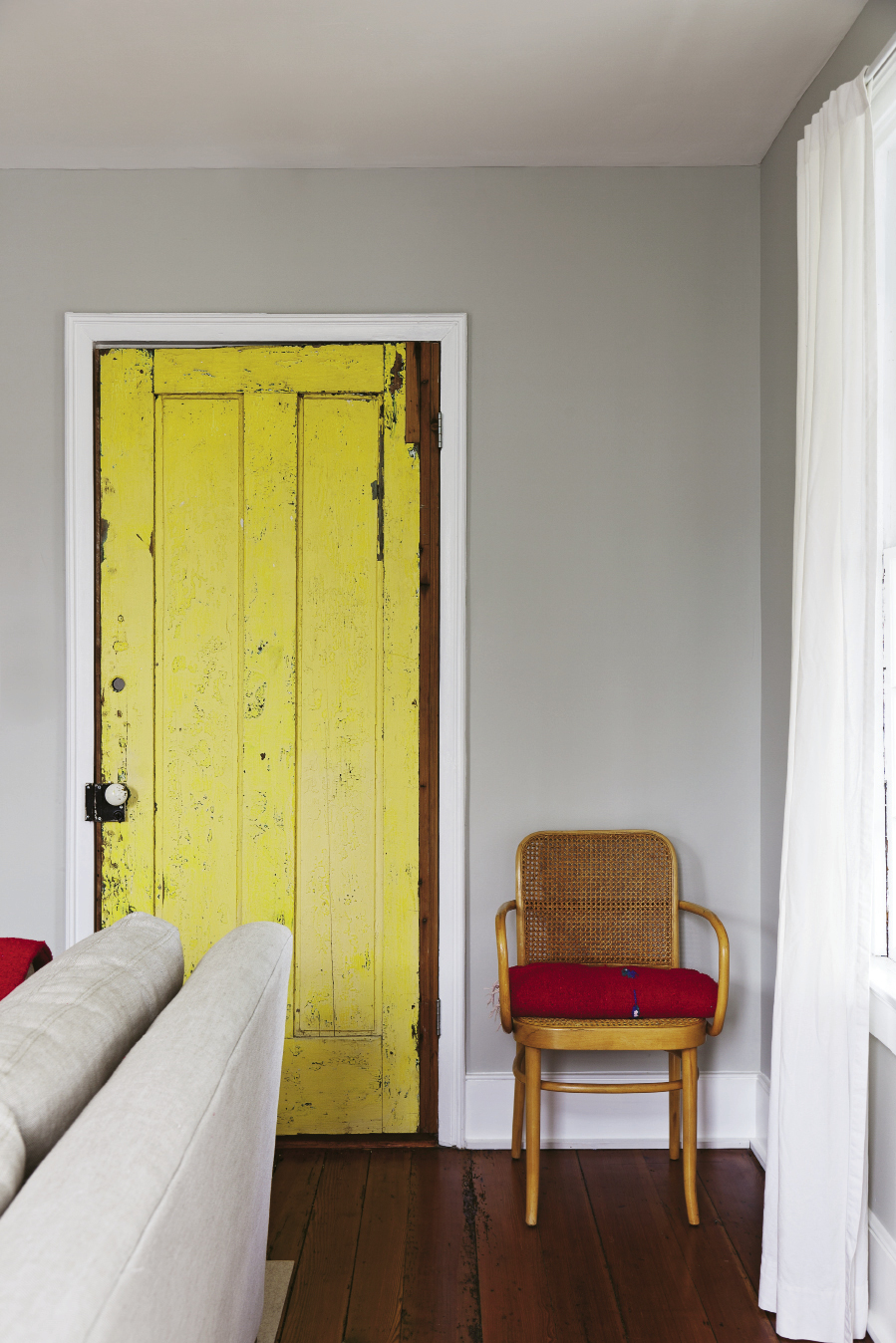 When the couple bought the building, this heart-pine door, originally the home’s back entry, was painted bright yellow. It’s been cleaned up and brought inside, but vestiges of the sunny paint color remain.