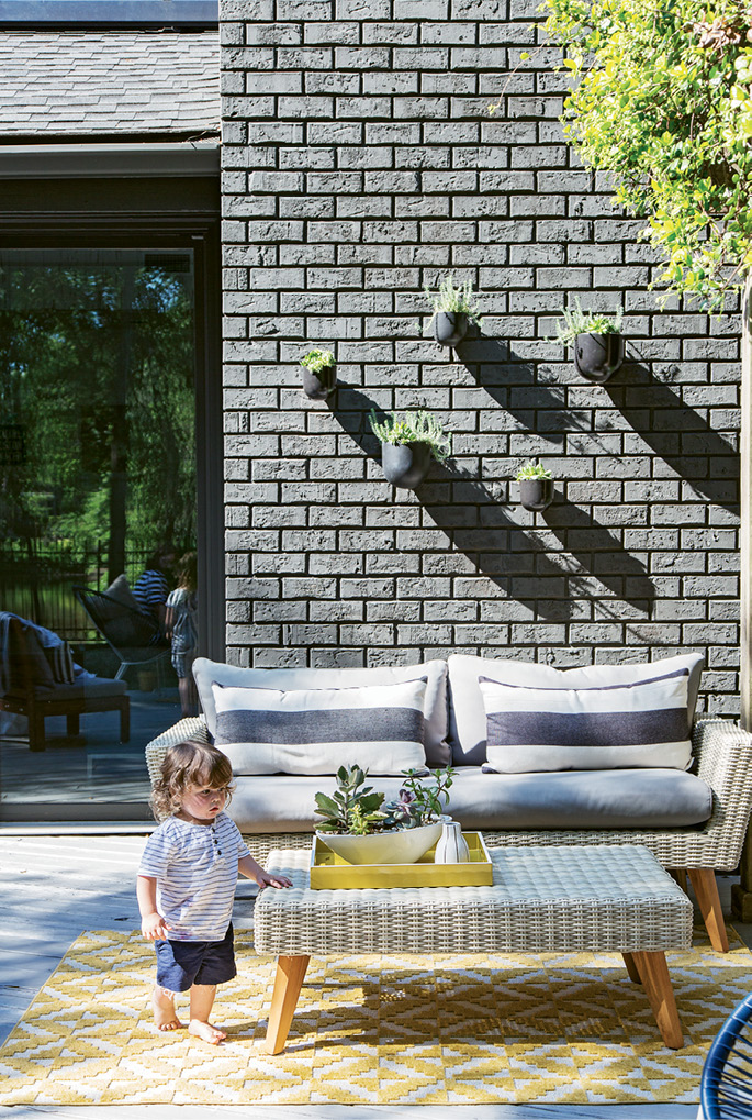 The space is outfitted with World Market furnishings in the same charcoal-and-white color scheme that dominates the interiors; wall-mounted planters from West Elm add a sculptural element to an exterior wall.