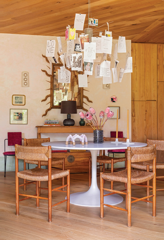 The dining room is anchored by an Eero Saarinen “Tulip” table surrounded by rush chairs by Charlotte Perriand and topped by an Ingo Maurer “Zettel’z 5” chandelier. “This was one of the first items that I selected when I initially conceived of the house,” she says.