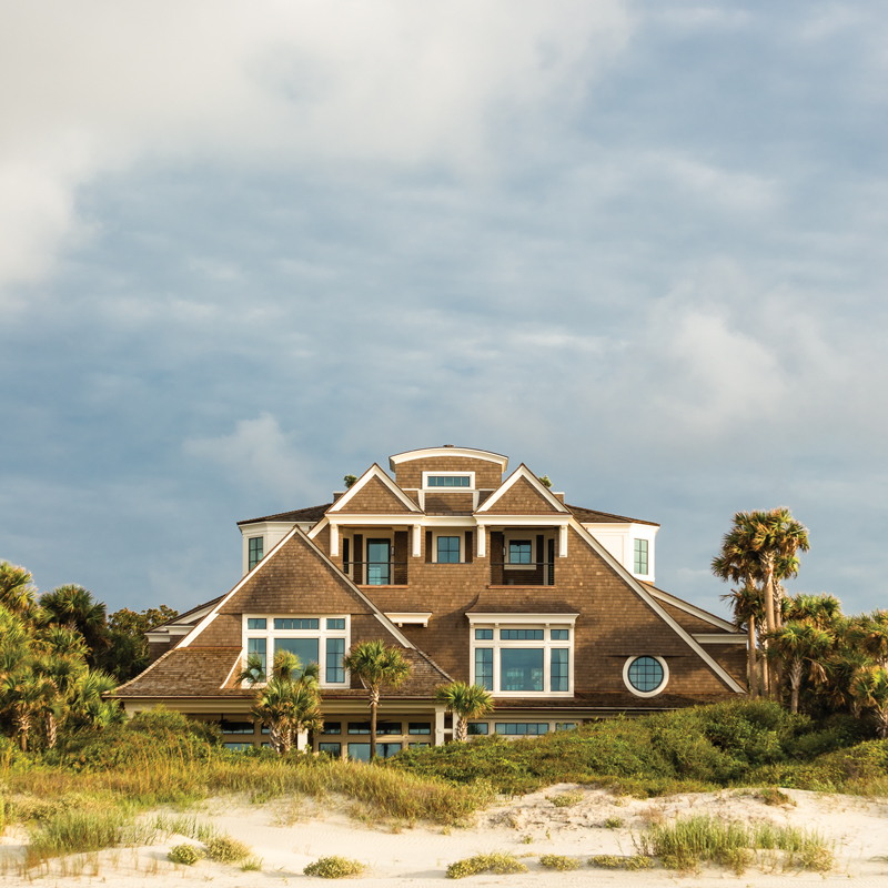 A towering dune allowed architect Jerry L. Hupy to conceal much of the home’s bulk, leaving just the second and third floors visible from the beach. A rooftop deck juxtaposed by two white dormer windows and some eyebrow detailing in the shingles add a touch of whimsy to the aesthetic.