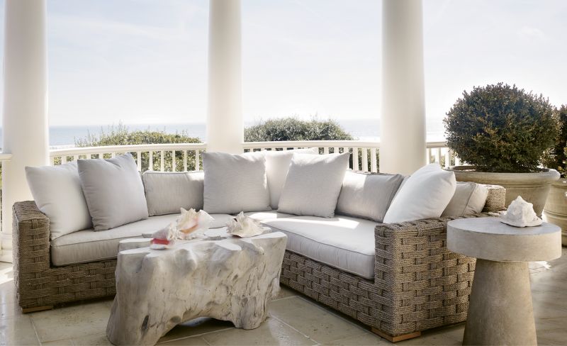 This columned porch provides both privacy and panoramic views. “The curved porches and their roofs shield the house from the neighbors, so you feel like you’re in the only house on the beach,” says architect Chris Rose. The outdoor furnishings, including a Restoration Hardware rope sectional, were selected to echo the classicism and Cape Cod influence of the architecture.