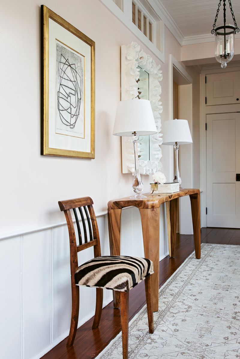 AN ELEGANT WELCOME: In the foyer, a vintage Biedermeier chair covered in Forsyth hide and an acacia wood console exude warmth, while a work by Otto Neumann in a gilt frame adds sophistication.