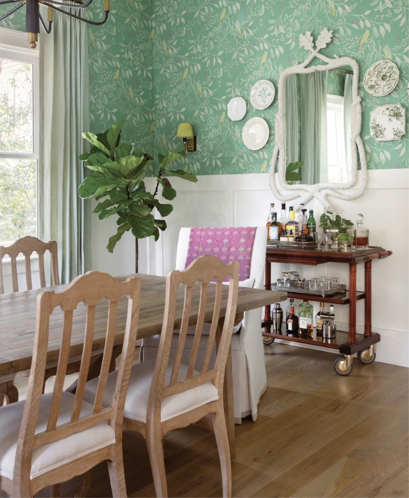 Mixed centuries: The daring Galbraith + Paul “Sumi” wallpaper in “Julep” brings color and visual interest into the formal dining room, where an antique dining table and chairs from Bungalow Classic and a former cheese cart from Maxim’s de Paris await a large family dinner. White wainscoting offsets the wallpaper and pays homage to the Victorian era of the home, while “I’On” fabric drapes from Palmette Home tie it all together.