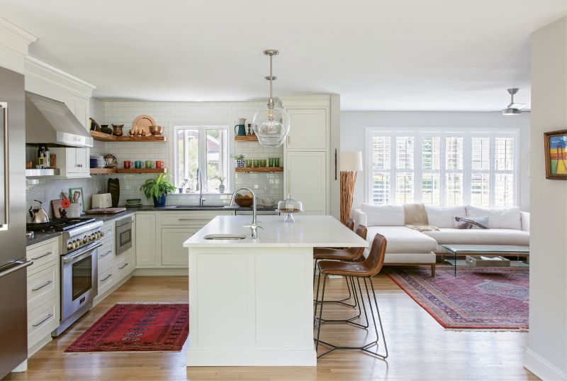 In the kitchen, handsome leather barstools from West Elm—tucked beneath a Calacatta Balena marble island and Pottery Barn globe pendants—offer comfy seating for guests.