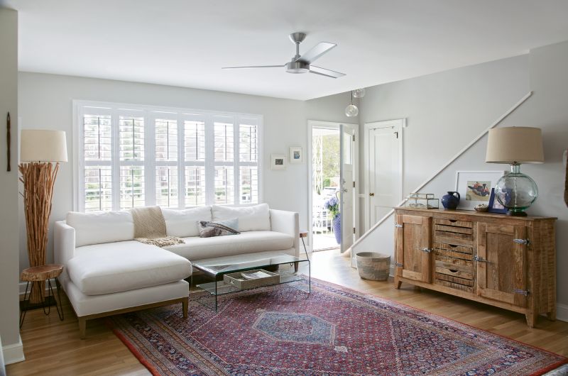 OLD &amp; NEW: The living room is filled with a mix of antiques (the area rug once belonged to Rachel’s grandparents), pieces purchased specifically for the space (like the GDC Home sectional and branchy floor lamp from Celadon), and furnishings acquired over time.