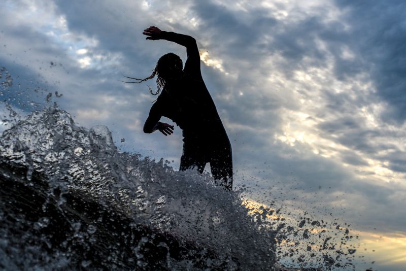 A surfer silhouetted by a winter sky