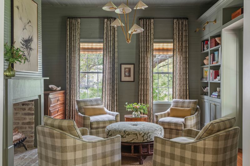 In the library, soft green walls (in Farrow &amp; Ball “Treron”) provide a cozy backdrop for four Highland House chairs covered in a buffalo check fabric from Fabricut.