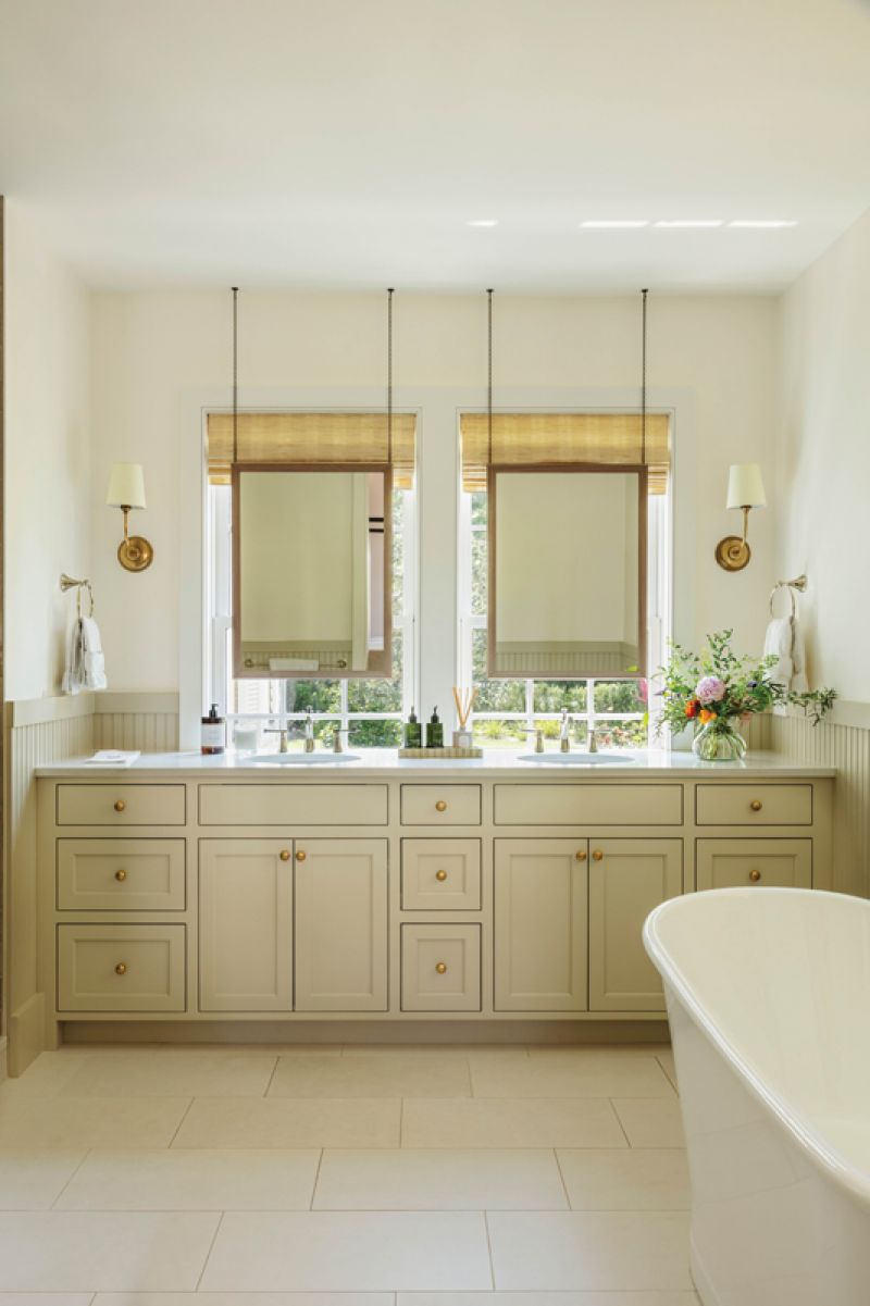 The adjoining bathroom is part of an earlier incarnation of the home. Custom mirrors hang in front of the windows, and a soaking tub sits opposite a walk-in shower.