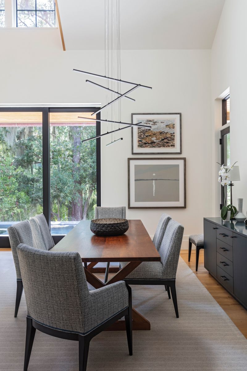 A striking light fixture the homeowners found at Visual Comfort in Charleston highlights two favorite works on the far wall. “We brought those pieces from our house in Maine; they’re both Maine artists, Alex Katz and the late Neil Welliver. They work so well together,” says the wife.