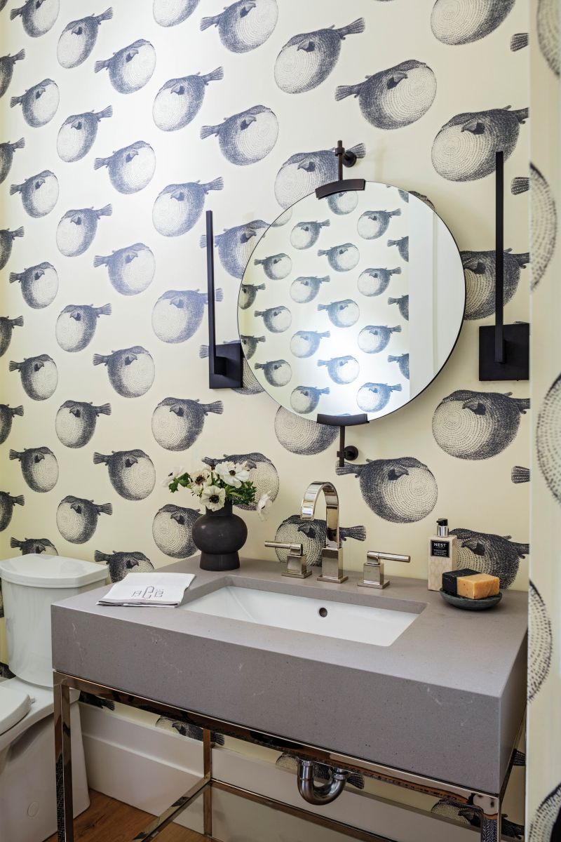 PLAYFUL POPS: Abnormals Anonymous’ graphic puffer fish wallpaper “Mr. Blow” combines with elegant, angular wall sconces from Visual Comfort in the downstairs powder room. “It’s fun to do this type of bold print in small spaces,” says Kuchera.