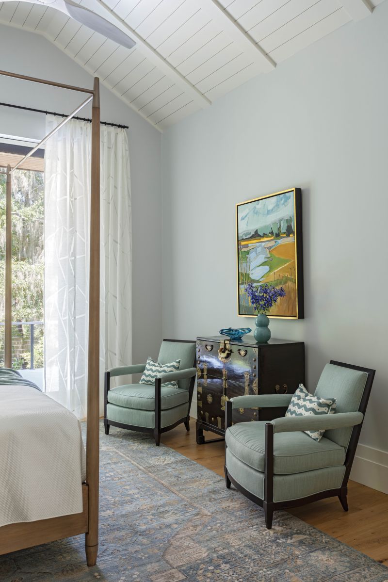 The Old Biscayne bed is offset by armchairs reupholstered in a pale green fabric and an antique dresser, above which another Ann Keane painting has pride of place.