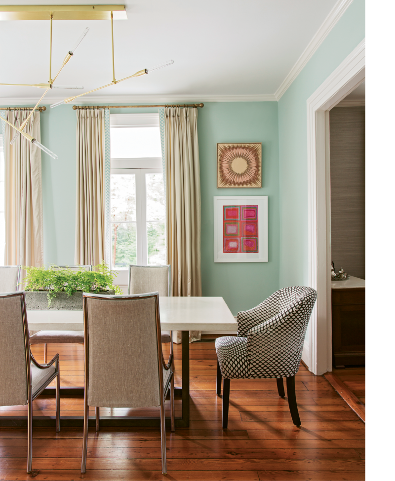 BALANCING ACT: In the formal dining room, a sleek concrete table and chrome-edged chairs ground sea-green walls and colorful artwork, such as this framed textile scored at High Point Market (top) and painting by area artist Linda Elksnin (bottom).