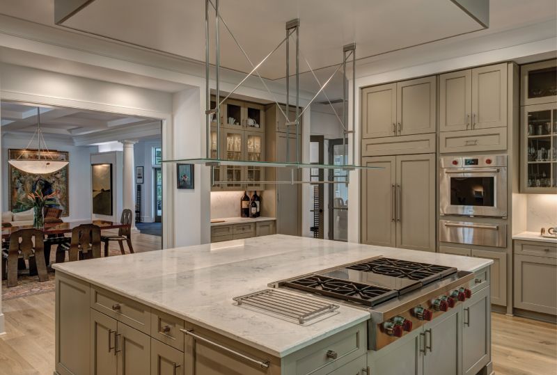 COOKING LIGHT: Abundant natural light is the main ingredient in the spacious kitchen, where an oversized island with quartz countertops offers a central gathering space. “We entertain a lot,” says the wife, who loves to cook but gives her husband props for “approaching chef status” with his culinary expertise.