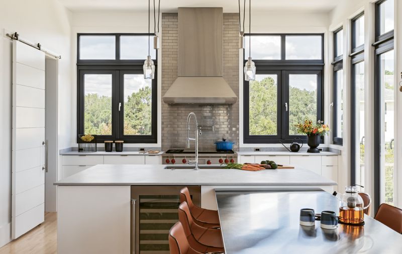 Stainless steel dominates the kitchen for practical reasons (it’s durable and easy to clean) and for visual effect—the ceiling-high backsplash with metal subway tile is a striking modern statement.