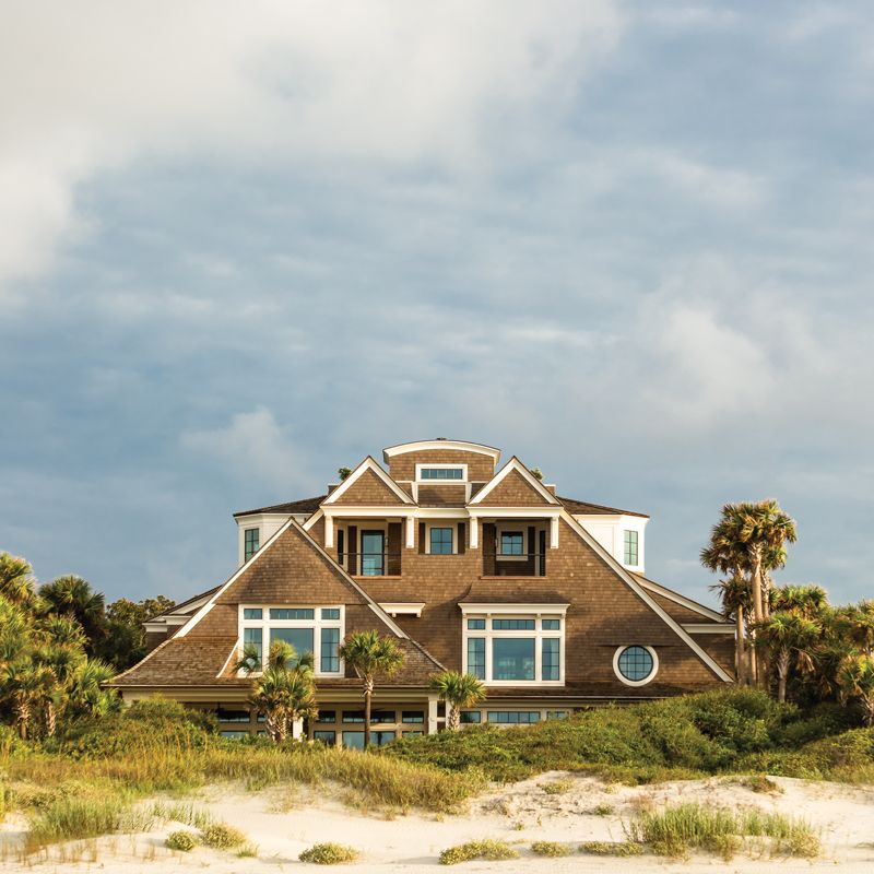 A towering dune allowed architect Jerry L. Hupy to conceal much of the home’s bulk, leaving just the second and third floors visible from the beach. A rooftop deck juxtaposed by two white dormer windows and some eyebrow detailing in the shingles add a touch of whimsy to the aesthetic.