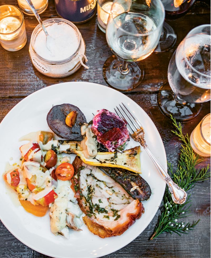 A plateful of fire-roasted delights, including porchetta, snapper, and veggies, is complemented by a cool heirloom  tomato salad.