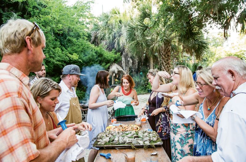 Guests peel shrimp and pry open juniper-roasted oysters only moments after Deihl pulls them from the fire pit. An evening breeze rustles the nearby juniper tree from which the garnishing sprigs were clipped.