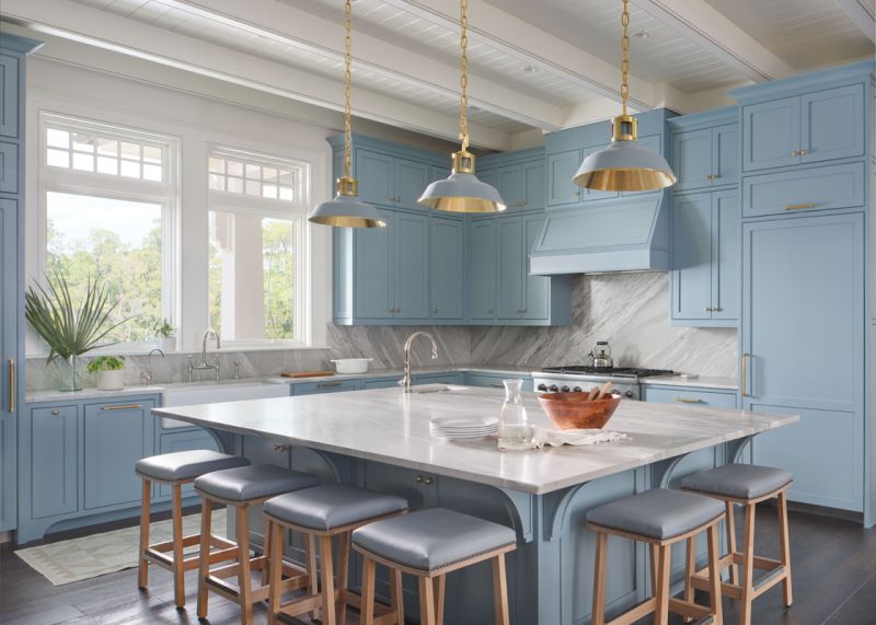 The open-plan kitchen and dining room pair light wood accents with Shaker-style cabinets painted in Benjamin Moore “Van Courtland Blue.” An expansive island topped with honed quartzite is a central gathering place.